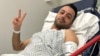 FILE - Pouria Zeraati, a presenter for independent Persian-language outlet Iran International, flashes a victory sign in a photo he posted of himself on X March 30, 2024, while hospitalized after a stabbing attack.