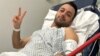 Pouria Zeraati, a presenter for independent Persian-language outlet Iran International, flashes a victory sign in a photo he posted of himself on X March 30, 2024, while hospitalized after a stabbing attack.