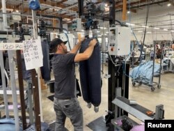 FILE - Seorang pekerja menggunakan balok pengamplasan untuk menghaluskan permukaan jeans biru baru di pabrik Saitex, Los Angeles, California, AS, 21 September 2022. (REUTERS/Timothy Aeppel)