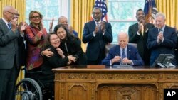 Interior Secretary Deb Haaland hugs Sen. Tammy Duckworth, D-Ill., after President Joe Biden, joined by civil rights leaders and elected officials, signs a proclamation in the Oval Office, Aug. 16, 2024, to designate the Springfield 1908 Race Riot National Monument. 