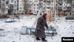 A woman walks on a playground after an apartment block was heavily damaged by a missile strike, amid Russia's attack on Ukraine, in Pokrovsk, Donetsk region, Feb. 15, 2023.