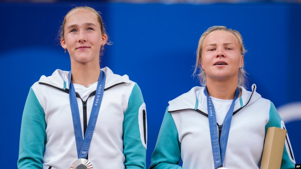 Mirra Andreeva and Diana Shnaider of Individual Neutral Athlete show their silver medals after losing to Sara Errani and Jasmine Paolini of Italy after women's doubles gold medal tennis match at Roland Garros stadium, at the 2024 Summer Olympics, Aug. 4, 2024, in Paris, France. 