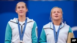 Mirra Andreeva and Diana Shnaider of Individual Neutral Athlete show their silver medals after losing to Sara Errani and Jasmine Paolini of Italy after women's doubles gold medal tennis match at Roland Garros stadium, at the 2024 Summer Olympics, Aug. 4, 2024, in Paris, France. 