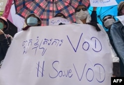 FILE - Supporters of online media outlet Voice of Democracy (VOD) hold placards in front of VOD office in Phnom Penh, Feb. 13, 2023.