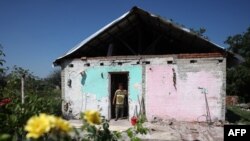 Local resident Valentina Ostapenko looks out from her damaged house in Topol's'ke village, Kharkiv region, Aug. 5, 2023, amid the Russian invasion in Ukraine.