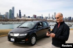 Pengemudi Uber Glen Snower sedang melihat ponselnya di samping mobil listrik BYD e6 di Chicago, Illinois, 18 Maret 2015. (Jim Young/REUTERS)