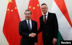 China's Director of the Office of the Central Foreign Affairs Commission Wang Yi shakes hands with Hungarian Foreign Minister Peter Szijjarto in Budapest, Hungary, February 20, 2023. REUTERS/Bernadett Szabo