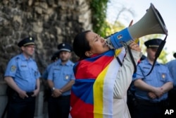 A Tibetan woman shouts into a loudspeaker against visiting Chinese President Xi Jinping, surrounded by Hungarian police, in Gellert Hill, Budapest, Hungary, May 9, 2024.