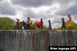 Children fill cans with water from a sand dam in Makueni County, Kenya, on Friday, March 1, 2024. (AP Photo/Brian Inganga)