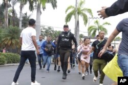 Police evacuate staff from the TC public television station after a group of armed men broke onto their set during a live broadcast, in Guayaquil, Ecuador, Tuesday, Jan. 9, 2024. (AP Photo/Cesar Munoz)