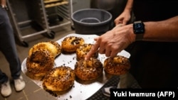 Andrew Martinez, pemilik toko bagel Bo's Bagels, menunjukkan bagels yang baru dipanggang di tokonya di Kota New York, 12 Juli 2023. (Foto: Yuki Iwamura/AFP)