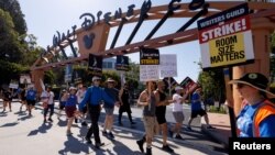 FILE — SAG-AFTRA actors and Writers Guild of America writers picket outside Disney Studios in Burbank, California, July 25, 2023. The guild said its members could return to work on Wednesday while a ratification vote takes place on a new contract with Hollywood studios. 