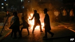 Ultra-Orthodox Jewish men burn trash during a protest against army recruitment, in Jerusalem, June 30, 2024. 