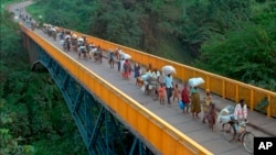 FILE - Rwandan refugees cross the bridge of Rumumo river, which marks the border between Tanzania and Rwanda, Dec. 14, 1996.