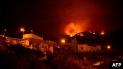 A picture taken in the night of Aug. 19, 2023, shows the fronts of the forest fire on hills above houses, in the Guimar valley on the Canary Island of Tenerife. 