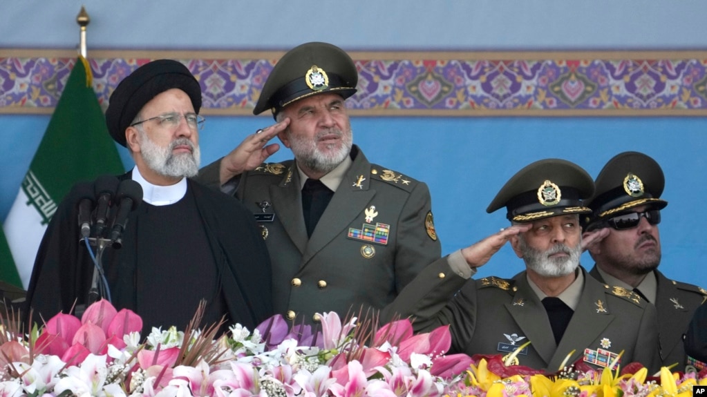 Iranian President Ebrahim Raisi, left, reviews an army parade commemorating Army Day in front of the mausoleum of the late revolutionary founder Ayatollah Khomeini just outside Tehran, April 18, 2023. 