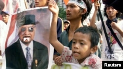 Pengunjuk rasa memegang poster mantan presiden Suharto pada aksi di Jakarta 12 Mei 1998. Aksi protes mahasiswa yang menuntut reformasi membantu mengakhiri pemerintahan Suharto pada 21 Mei 1998 (foto: dok). 