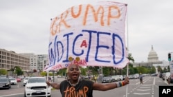 FILE - The US Capitol is seen in the distance as Nadine Seiler holds a banner at the E. Barrett Prettyman US Federal Courthouse, Aug. 3, 2023, in Washington.