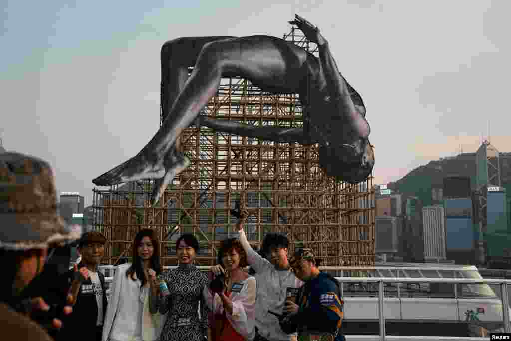 People take pictures with public art instalation titled &quot;GIANTS: Rising Up&quot; by the French artist JR, at Harbour City, Hong Kong.