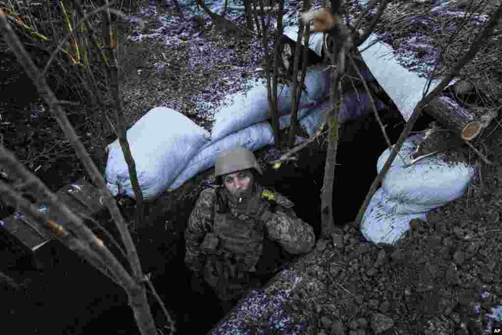 Украинский военный курит в окопе на линии фронта рядом с Бахмутом, 11 января 2023. (AP Photo/Evgeniy Maloletka)