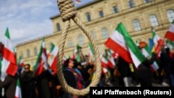 (FILE) A noose is seen as people hold Iranian flags during a protest in Germany.