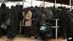 FILE - Female residents from former Islamic State-held areas in Syria line up for aid at al-Hol camp in Hasakah province, Syria, March 31, 2019.