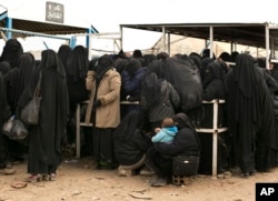 FILE - Female residents from former Islamic State-held areas in Syria line up for aid at al-Hol camp in Hasakeh province, Syria, March 31, 2019.