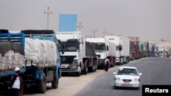 FILE - Trucks stand at the Rafah border crossing between Egypt and the Gaza Strip, amid the conflict between Israel and Palestinian Islamist group Hamas, April 25, 2024.