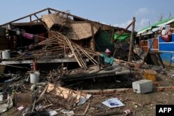 Seorang wanita Rohingya duduk di dekat rumahnya yang hancur di kamp pengungsi Ohn Taw Chay di Sittwe pada 16 Mei 2023. (Foto: AFP)