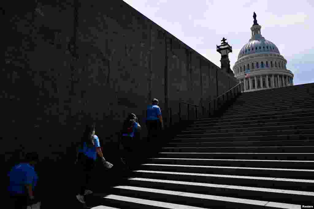 Visitors ascend the last remaining part of shade of a set of stairs on Capitol Hill amid a heat wave in Washington, June 19, 2024.