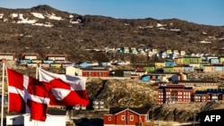 FILE - The Greenlandic and Danish, left, flags flutter in Ilulissat, western Greenland, June 29, 2022.