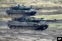 FILE - Two Leopard 2 tanks seen in action at the Bundeswehr tank battalion 203 at the Field Marshal Rommel Barracks in Augustdorf, Germany, Feb. 1, 2023.