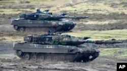 FILE - Two Leopard 2 tanks seen in action at the Bundeswehr tank battalion 203 at the Field Marshal Rommel Barracks in Augustdorf, Germany, Feb. 1, 2023.