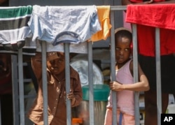Children look through a fence at a shelter for families displaced by gang violence, in Port-au-Prince, Haiti, March 13, 2024.