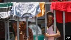 Children look through a fence at a shelter for families displaced by gang violence, in Port-au-Prince, Haiti, March 13, 2024.