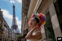 Hu Xiao, from China, poses as her friends take her photograph near the Eiffel Tower at the 2024 Summer Olympics, July 28, 2024, in Paris, France.