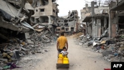 A Palestinian man pulls a boy on a cart on a street lined with destroyed buildings in Khan Yunis in the southern Gaza Strip, May 2, 2024, amid the ongoing conflict between Israel and the militant Hamas movement.