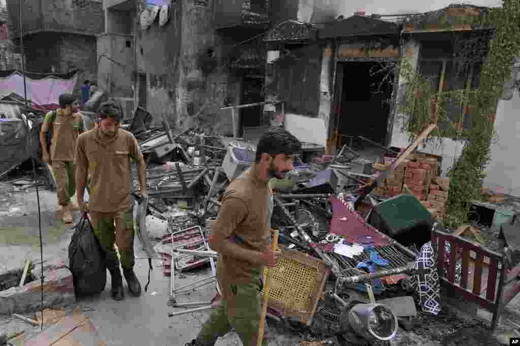 Police officers walk through the rubble of homes vandalized by an angry Muslim mob, Aug. 17, 2023. 