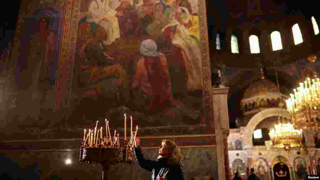 Жена пали свеќа додека присуствува на миса на Божиќ во катедралата Свети Александар Невски во Софија, Бугарија.
