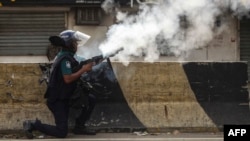 A Bangladeshi policeman fires tear shells to disperse anti-quota protesters during a clash in Dhaka on July 19, 2024.