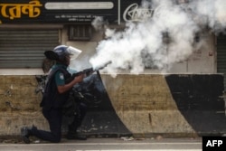 A Bangladeshi policeman fires tear gas shells to disperse anti-quota protesters during a clash in Dhaka, July 19, 2024.