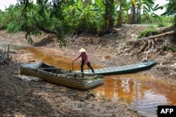 Seorang petani melintasi kanal yang hampir kering seluruhnya di provinsi Ca Mau, Vietnam selatan, di tengah gelombang panas yang berkepanjangan, 23 Februari 2024. (Tan Dien / AFP)