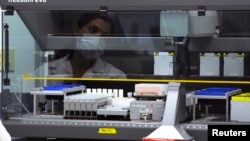 FILE - A forensic scientist watches a machine analyze samples in the DNA lab during a tour of the Orange County, California Crime Lab in Santa Ana, California August 14, 2013. 