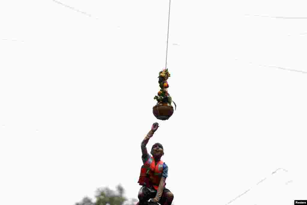 A devotee tries to break a clay pot containing curd during the celebrations to mark the Hindu festival of Janmashtami in Mumbai, India.