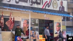FILE - People are see in front of a government-subsidized store displaying posters of Egyptian President Abdel Fattah el-Sissi on its facade, in Cairo, Egypt, Feb. 27, 2023. 