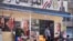 FILE - People are see in front of a government-subsidized store displaying posters of Egyptian President Abdel Fattah el-Sissi on its facade, in Cairo, Egypt, Feb. 27, 2023. 
