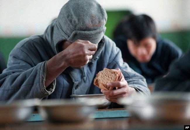 FILE – An unidentified prisoner holds a piece of bread inside Corrective Labor Colony No. 22 in the village of Leplei, some 600 kilometers southeast of Moscow, on Nov. 13, 1996. (AP Photo/Alexander Zemlianichenko, File)