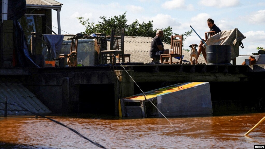 ARCHIVO - Hombres sentados en el techo de una casa en una zona inundada en Canoas, estado de Rio Grande do Sul, Brasil, 14 de mayo de 2024.