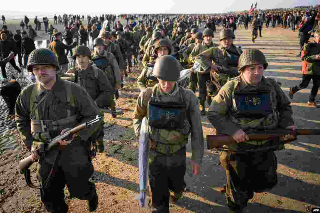 Enthusiasts dressed in replica U.S. Army WWII-era military attire parade along Utah Beach, France, June 6, 2024 during the &quot;D-Day&quot; commemorations marking the 80th anniversary of the World War II Allied landings in Normandy.