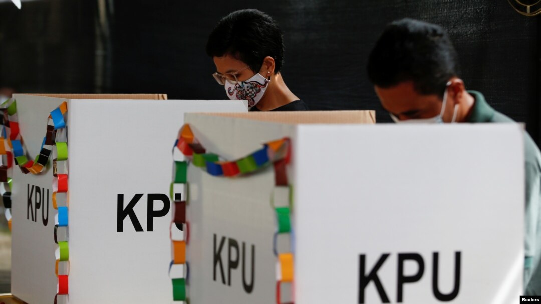 Pemilih yang memakai masker sedang mencoblos surat suara mereka di TPS saat pemilihan kepala daerah di Tangerang, 9 Desember 2020. (Foto: REUTERS/Willy Kurniawan)